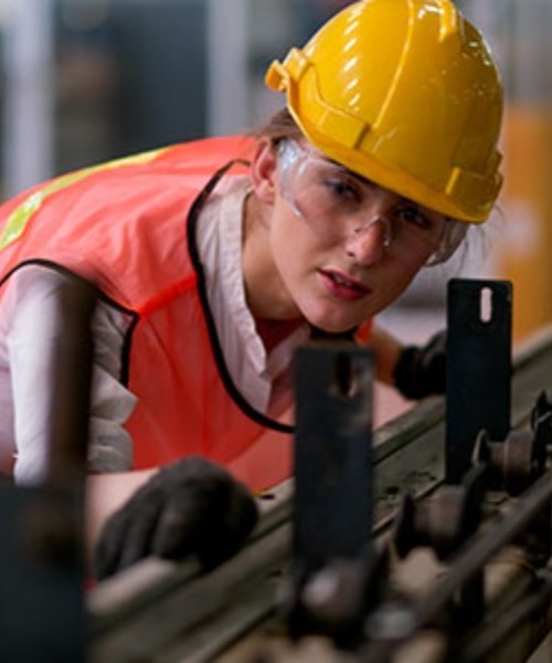 Employee with safety equipment on working on machinery